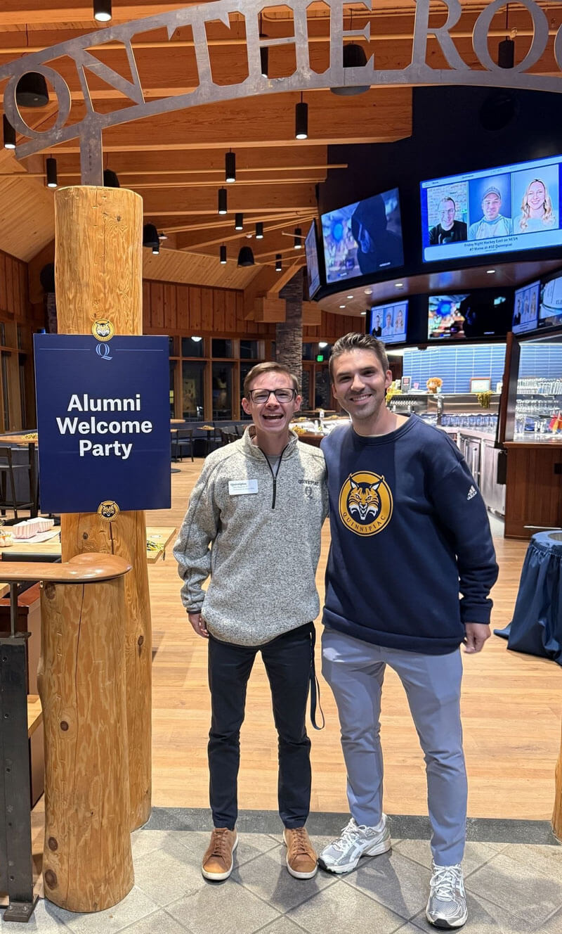 Kyle Adams and John Shepherd pose for a photo at On the Rocks for an alumni event