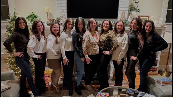 Quinnipiac alumna Kimberly Saccucci posing for a picture in a living room with several friends from Quinnipiac