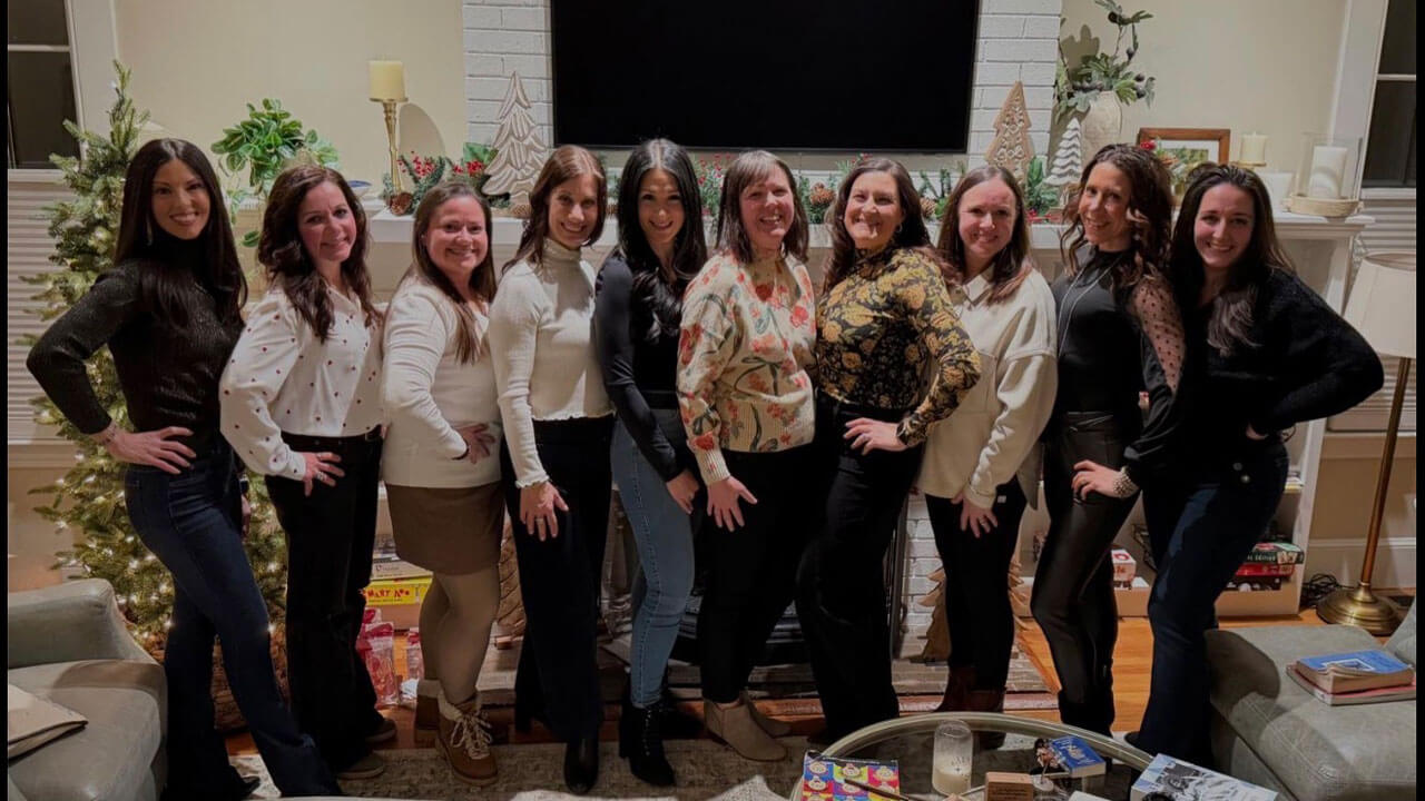 Quinnipiac alumna Kimberly Saccucci posing for a picture in a living room with several friends from Quinnipiac