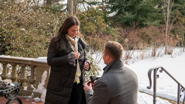 Anthony Schiano kneels with a ring with Caroline Ix in a garden
