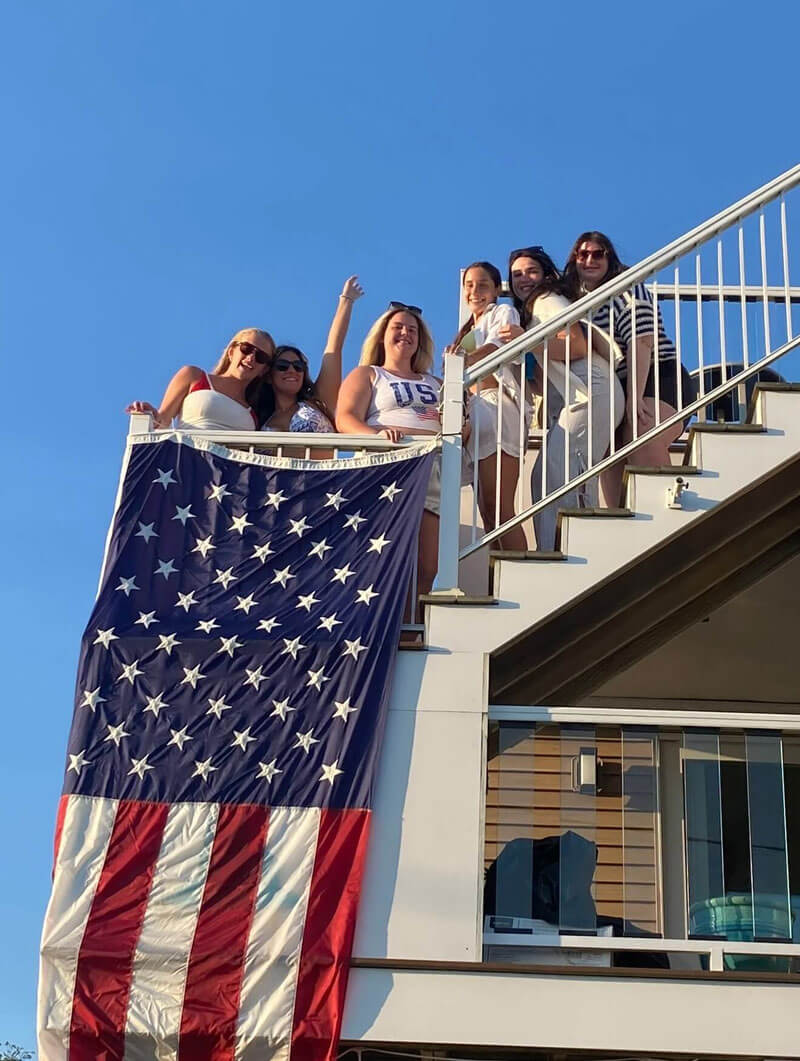 Quinnipiac alumna Bryanna Paternostro poses for a picture with classmates on a boat with the American flag