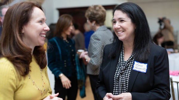 Two participants in business attire speak to each other at a women in business event