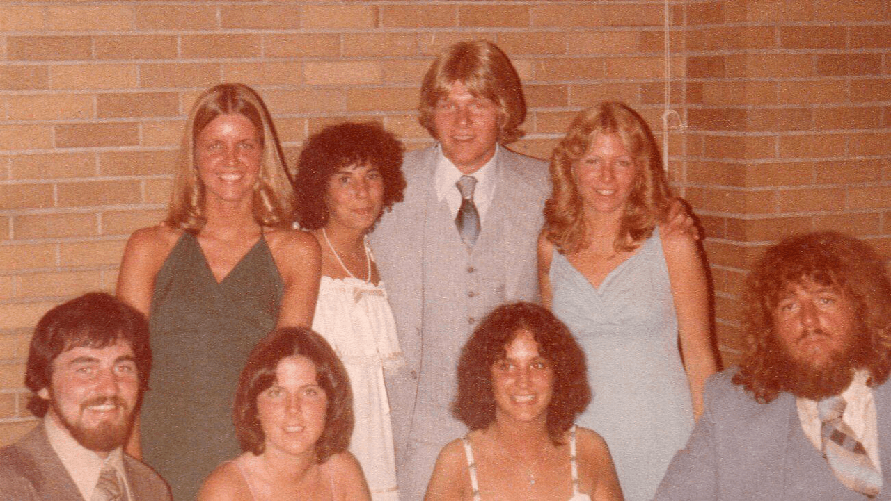 8 people dressed up smile for a photo at a wedding