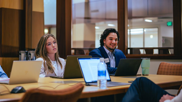 Three law students with laptops in the law library speaking to a career professional