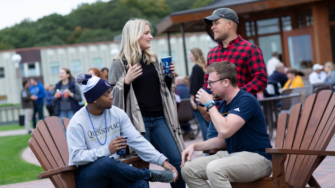 A group of Quinnipiac alumni sit on the Rocky Top porch and talk