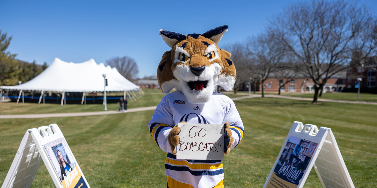 Boomer holding a Go Bobcats sign on the quad