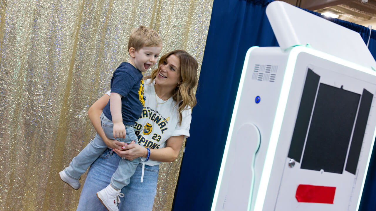 Person holds child smiling for a photobooth