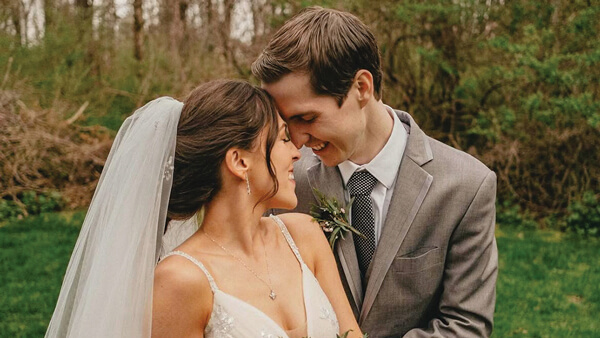 Lauren (Stalzer) Smith and husband embrace with a bouquet of white flowers