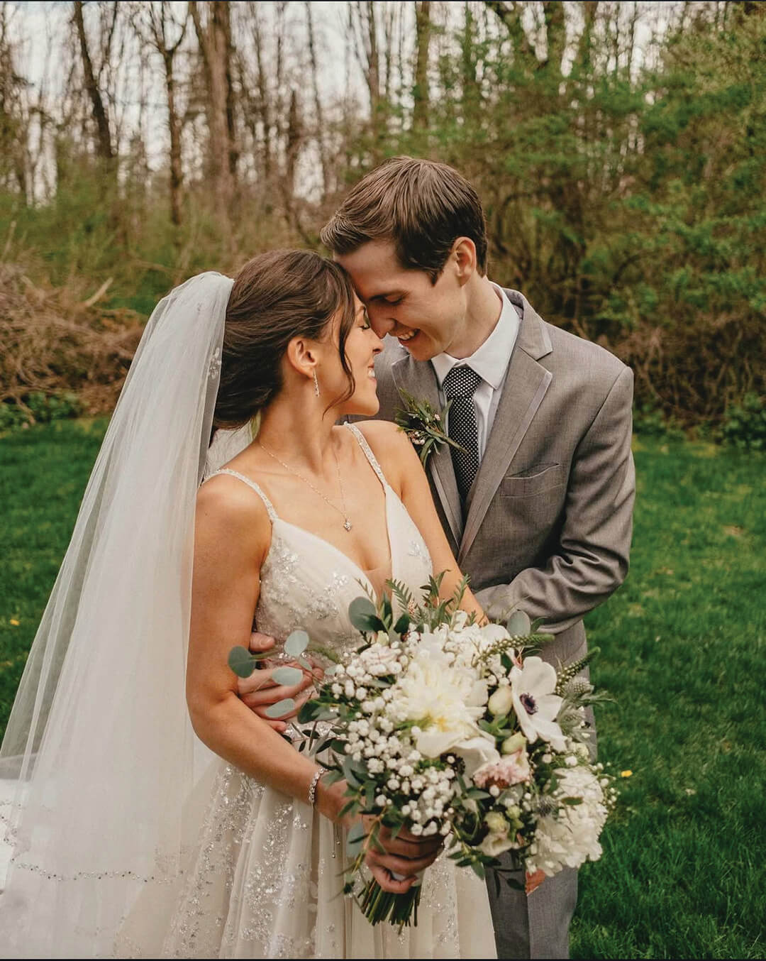 Lauren (Stalzer) Smith and husband embrace with a bouquet of white flowers