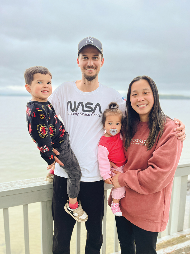 Emily Van Fleet and her husband hold their two children with a beach in the background